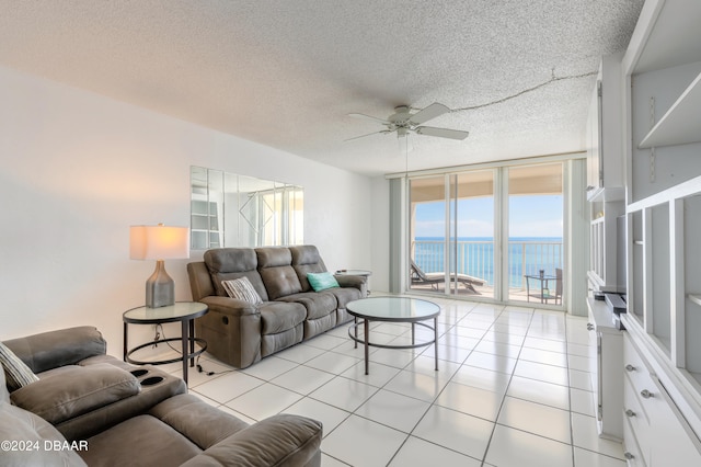 tiled living room with floor to ceiling windows, a water view, a textured ceiling, and ceiling fan