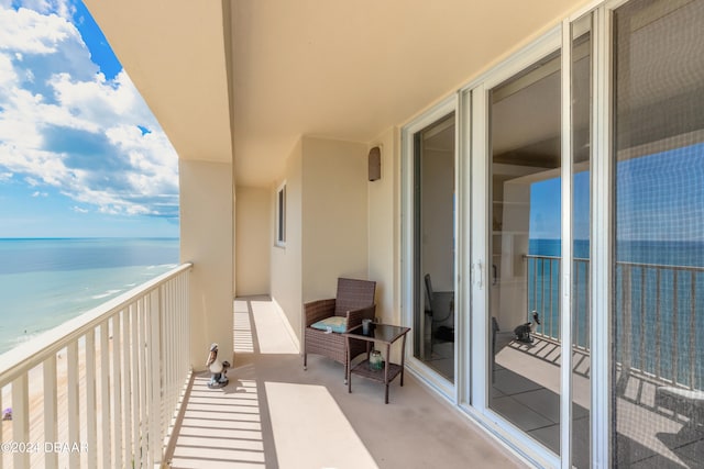 balcony with a water view and a view of the beach