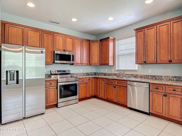 189 Perfect Dr, Daytona Beach, FL 32124 - kitchen with stainless steel appliances, brown cabinets, stone countertops, recessed lighting, and a textured ceiling