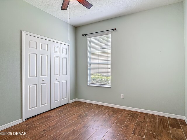 189 Perfect Dr, Daytona Beach, FL 32124 - unfurnished bedroom featuring dark wood finished floors, multiple windows, a closet, a textured ceiling, and ceiling fan