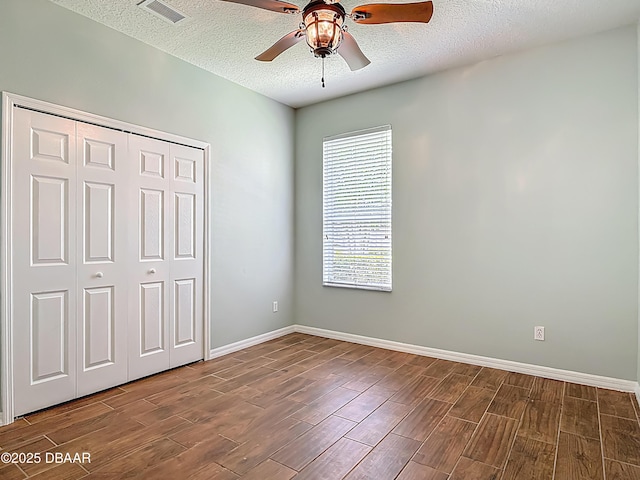 189 Perfect Dr, Daytona Beach, FL 32124 - unfurnished bedroom with dark wood-style flooring, a textured ceiling, a closet, and a ceiling fan