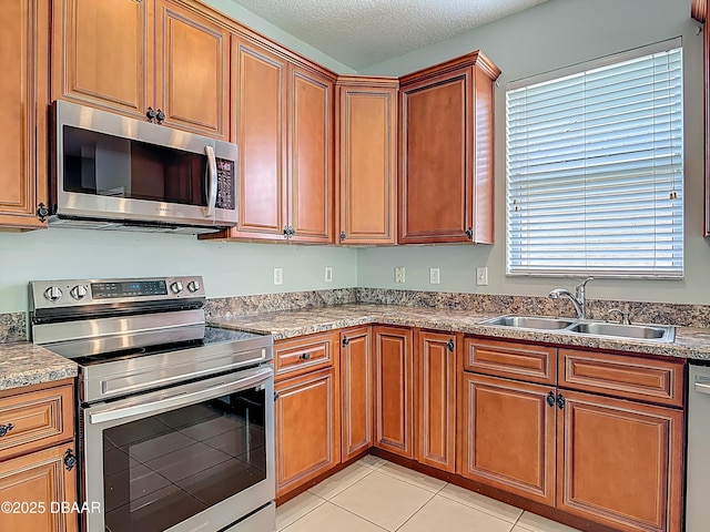 189 Perfect Dr, Daytona Beach, FL 32124 - kitchen with stainless steel appliances, brown cabinetry, a textured ceiling, and light tile patterned floors