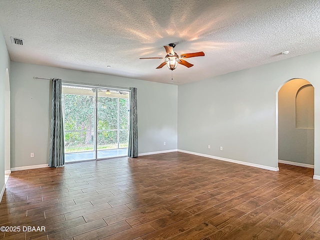 189 Perfect Dr, Daytona Beach, FL 32124 - empty room featuring arched walkways, ceiling fan, dark wood-style flooring, and a textured ceiling