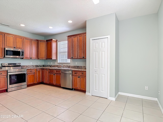 189 Perfect Dr, Daytona Beach, FL 32124 - kitchen with appliances with stainless steel finishes, recessed lighting, light tile patterned flooring, a textured ceiling, and brown cabinets