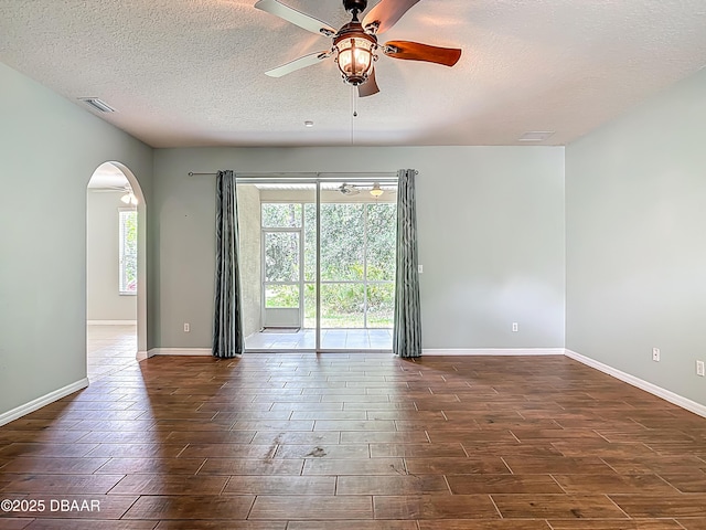 189 Perfect Dr, Daytona Beach, FL 32124 - spare room featuring arched walkways, dark wood-style flooring, ceiling fan, and a textured ceiling