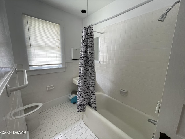 bathroom with shower / bath combo with shower curtain, tile walls, tile patterned floors, and toilet