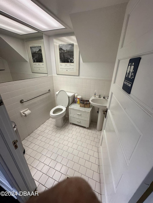 bathroom featuring toilet, tile patterned floors, and tile walls