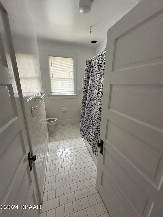 bathroom featuring curtained shower, toilet, and tile patterned floors