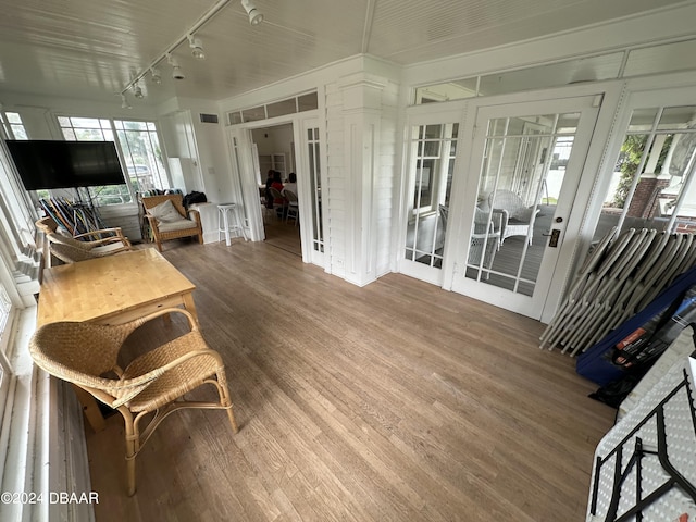 sunroom with rail lighting, a wealth of natural light, and french doors