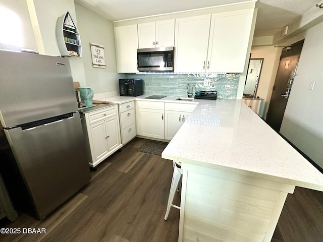 kitchen with white cabinets, a sink, a peninsula, and appliances with stainless steel finishes