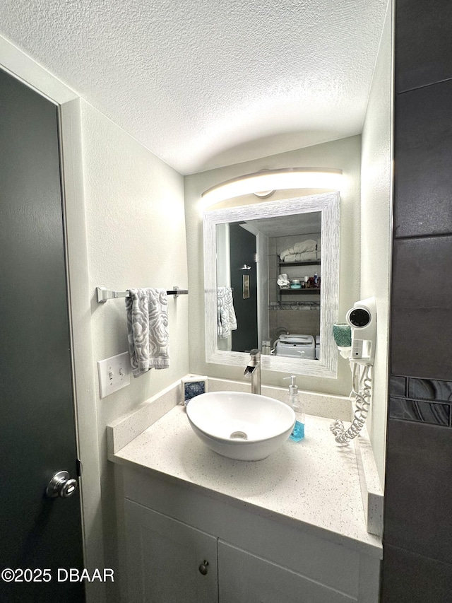 bathroom featuring a textured wall, vanity, and a textured ceiling