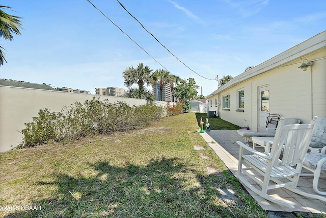 view of yard featuring central AC and fence