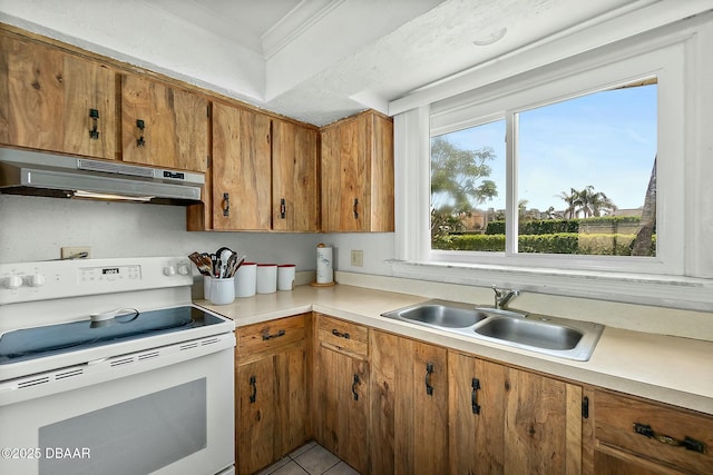 kitchen with electric range, a sink, light countertops, under cabinet range hood, and brown cabinets