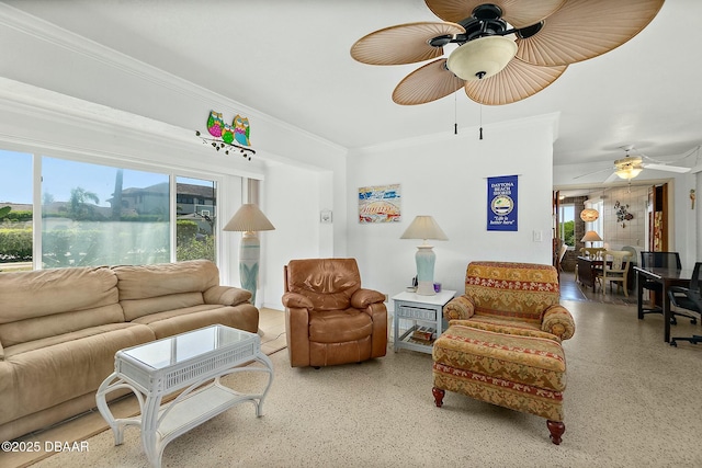 living area with speckled floor, ornamental molding, and a ceiling fan