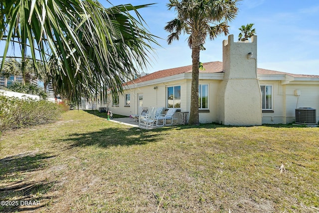 rear view of property featuring a patio, central air condition unit, a yard, and stucco siding