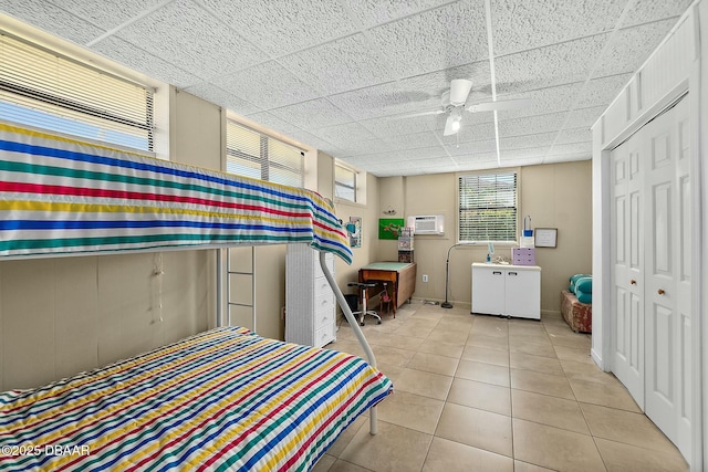 bedroom with tile patterned floors, a paneled ceiling, and a closet