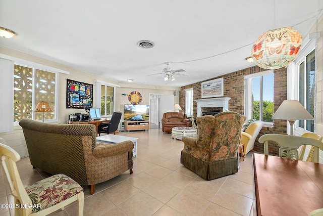 living area with visible vents, a brick fireplace, brick wall, light tile patterned floors, and a ceiling fan