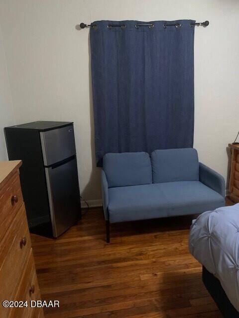 bedroom with dark wood-type flooring and freestanding refrigerator