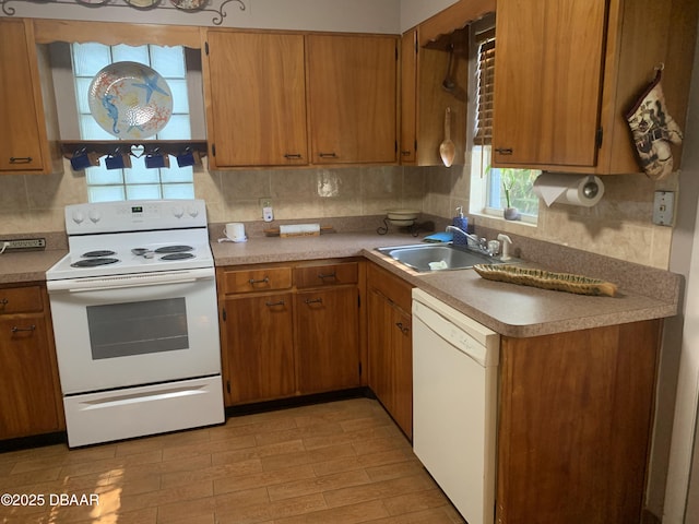 kitchen featuring white appliances, decorative backsplash, brown cabinetry, light wood-type flooring, and a sink