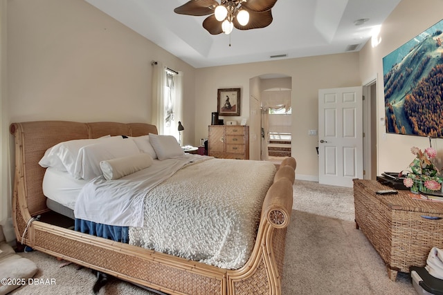 carpeted bedroom featuring ceiling fan and a tray ceiling