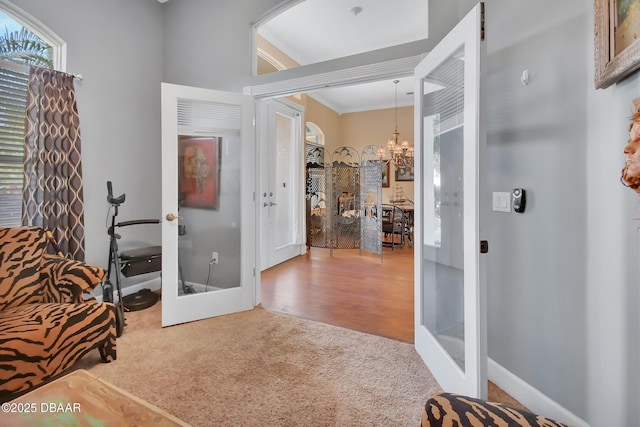 corridor with carpet floors, french doors, and a chandelier