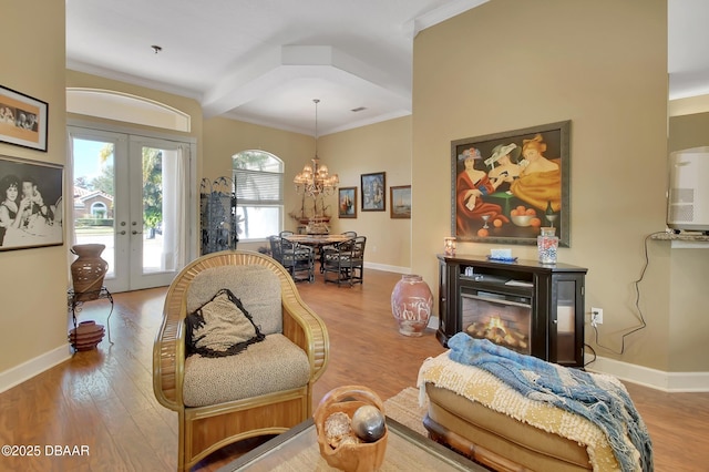 living room with wood-type flooring, ornamental molding, french doors, and a chandelier