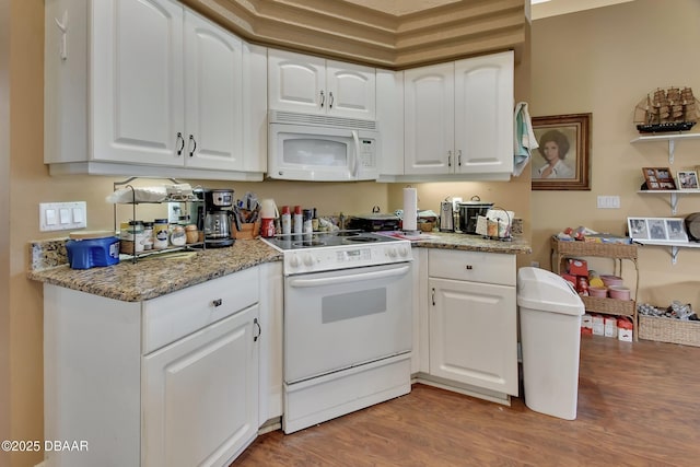 kitchen featuring white cabinetry, light stone countertops, light wood-type flooring, and white appliances