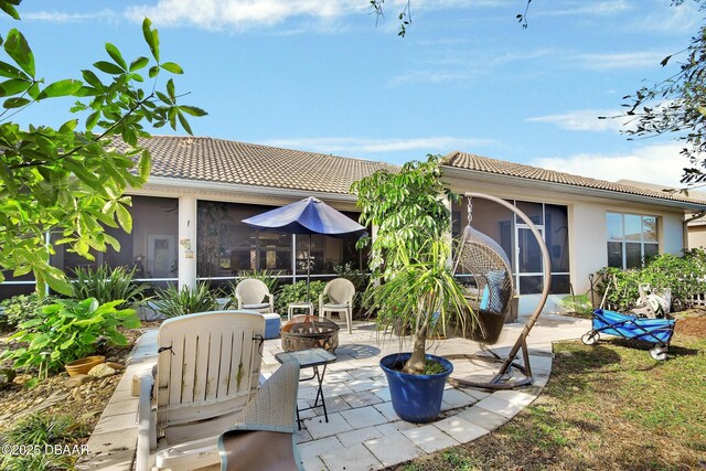 exterior space with a sunroom, a patio, and a fire pit