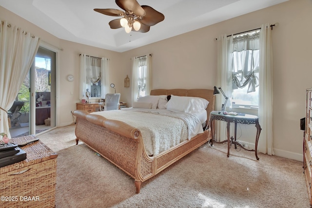 carpeted bedroom with ceiling fan, access to exterior, and a raised ceiling