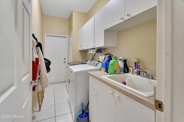 washroom featuring light tile patterned flooring, sink, cabinets, a textured ceiling, and washing machine and dryer