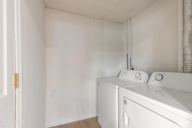 washroom featuring washer and clothes dryer, wood walls, and light wood-type flooring