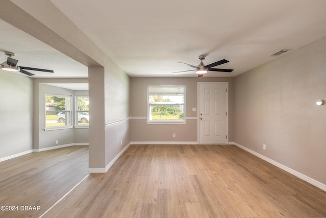 empty room with a wealth of natural light, ceiling fan, and light hardwood / wood-style floors