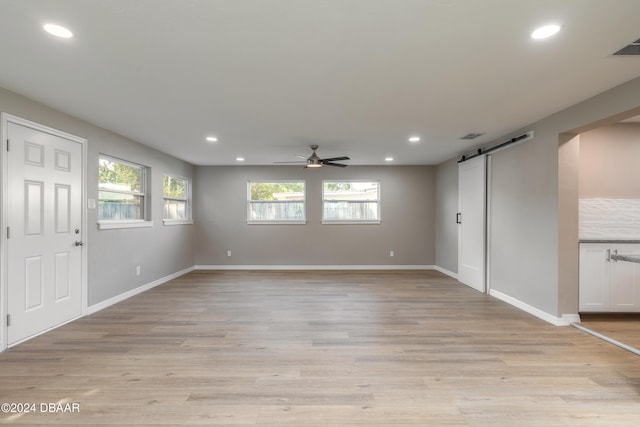 interior space featuring light hardwood / wood-style floors, a barn door, and ceiling fan