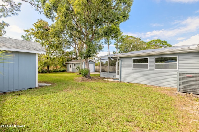 view of yard with a garage, central AC, and an outdoor structure