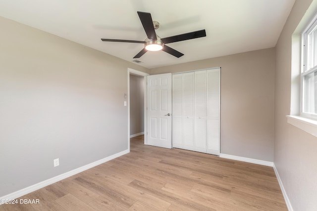 unfurnished bedroom featuring ceiling fan, a closet, and light wood-type flooring