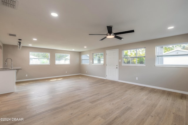 unfurnished living room featuring light wood-type flooring, ceiling fan, and a healthy amount of sunlight