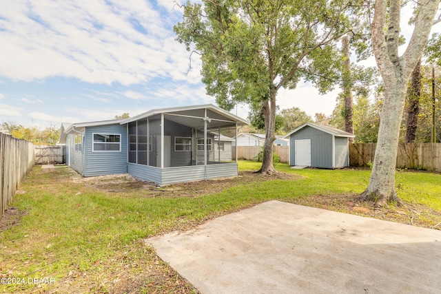 rear view of house with a patio area, a sunroom, a yard, and a storage unit