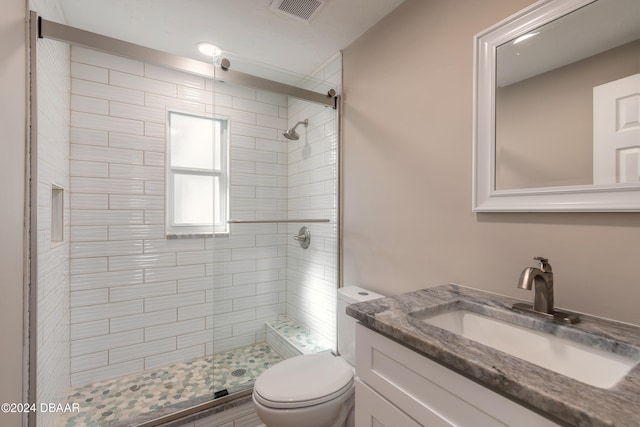 bathroom featuring toilet, vanity, and a shower with door