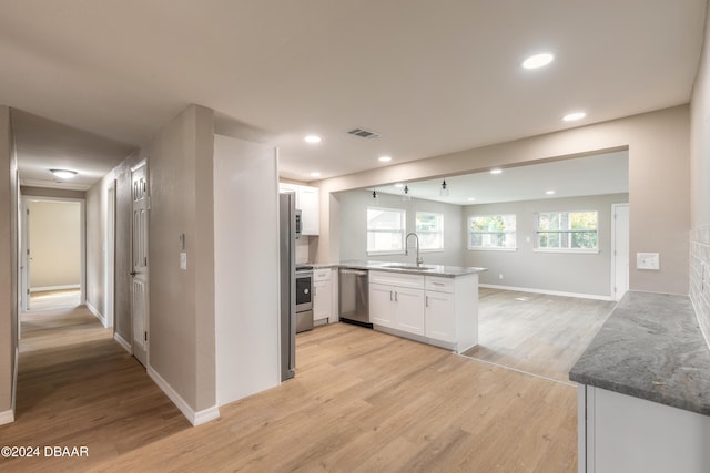 kitchen with light hardwood / wood-style flooring, appliances with stainless steel finishes, stone countertops, and white cabinets