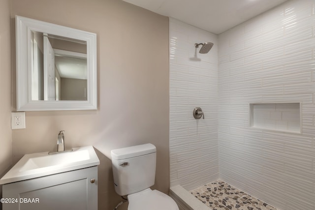 bathroom with vanity, toilet, and tiled shower