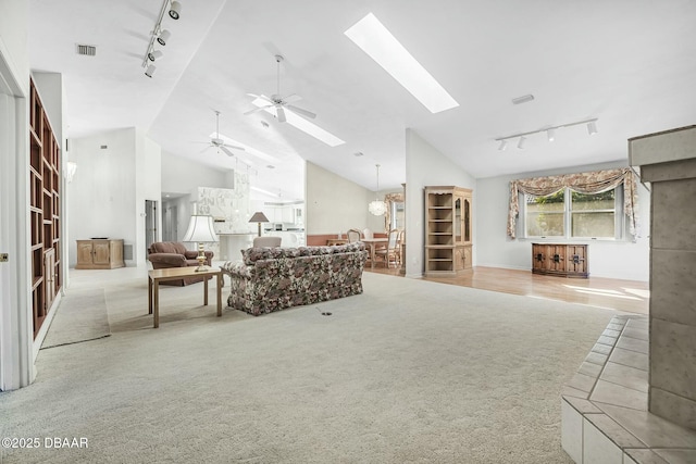 carpeted living room featuring high vaulted ceiling, ceiling fan, a skylight, and track lighting