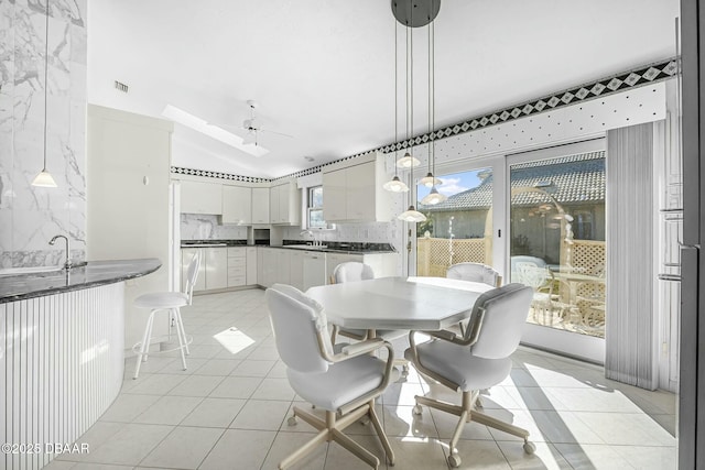 tiled dining area with ceiling fan, sink, and lofted ceiling