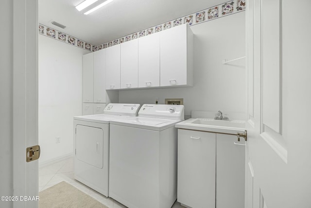 laundry room with light tile patterned flooring, cabinets, sink, and washing machine and clothes dryer