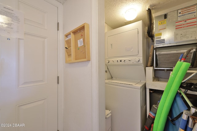 clothes washing area with a textured ceiling, stacked washer and clothes dryer, and heating unit