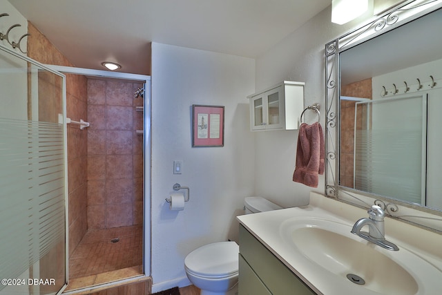 bathroom featuring a shower with door, vanity, and toilet