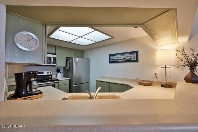 4453 S Atlantic Ave Unit 1080, Ponce Inlet, FL 32127 - kitchen featuring stainless steel appliances, green cabinets, light countertops, and lofted ceiling