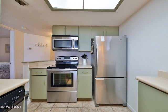 kitchen featuring a textured ceiling, light tile patterned floors, green cabinetry, and stainless steel appliances