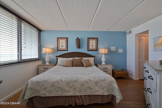 bedroom featuring dark hardwood / wood-style floors, a textured ceiling, and a closet