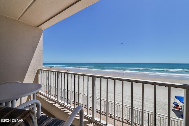 balcony featuring a view of the beach and a water view