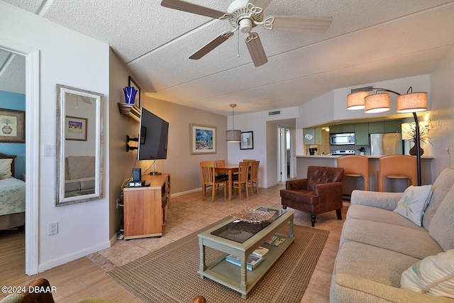 living room with ceiling fan and a textured ceiling